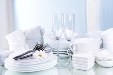 Set of white dishes on table on light background clipart