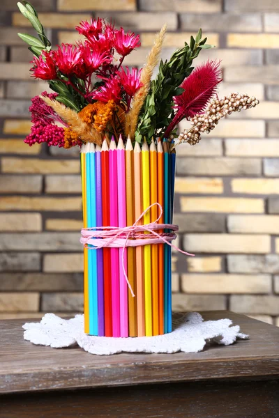 Bellissimi fiori in colorato vaso matite su sfondo muro di mattoni — Foto Stock