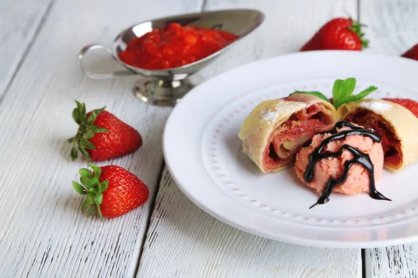 Tasty homemade strudel with ice-cream, fresh strawberry and mint leaves on plate, on wooden background — Stock Photo, Image