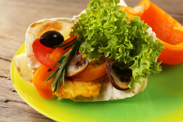 Envoltura vegetal llena de pollo y verduras frescas en la mesa de madera, de cerca — Foto de Stock