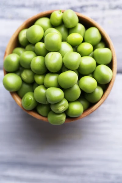 Green peas in wooden bowl on wooden background — Stock Photo, Image