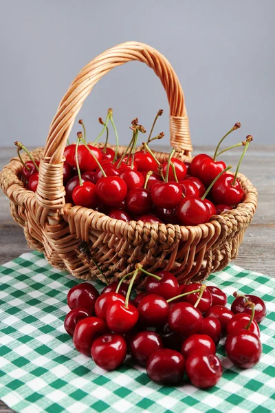 Sweet cherries in wicker basket on wooden table — Stock Photo, Image