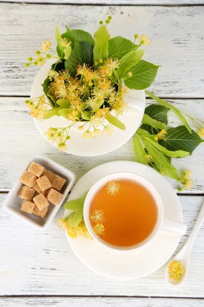 Sabroso té de hierbas con flores de tilo en la mesa de madera —  Fotos de Stock