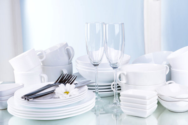 Set of white dishes on table on light background