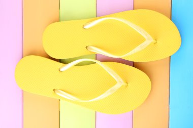 Renkli ahşap arka planda parlak parmak arası terlikler