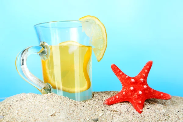 Koude thee in zand op blauwe achtergrond — Stockfoto