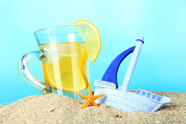 Koude thee in zand op blauwe achtergrond — Stockfoto