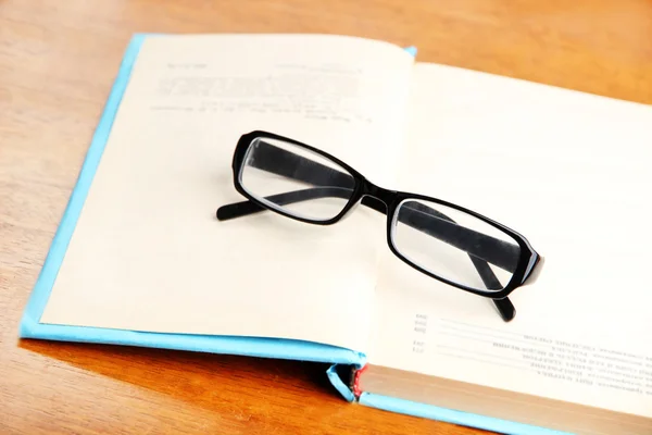 Samenstelling met oude boek, bril, op houten achtergrond — Stockfoto