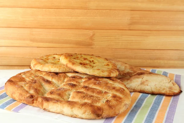 Pita ekmekler üzerinde ahşap zemin üzerinde masa örtüsü — Stok fotoğraf