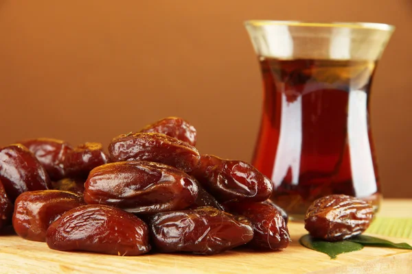 Dried dates with cup of tea on table on brown background — Stock Photo, Image