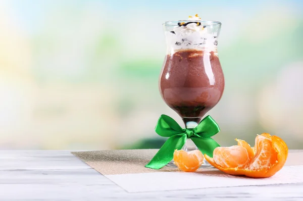 Tasty dessert with chocolate, cream and orange sauce, on napkin. on wooden table, on light background — Stock Photo, Image