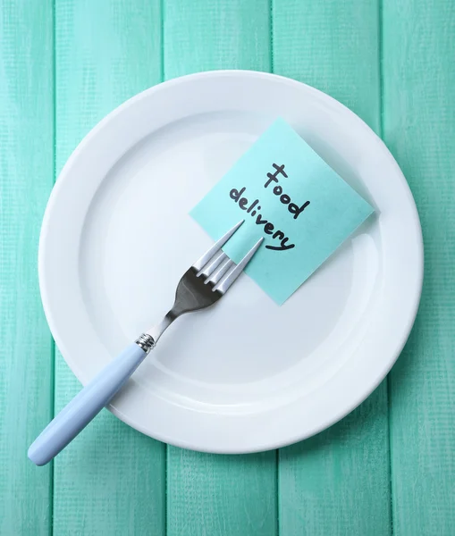 Note paper with message  attached to fork, on plate, on color wooden background — Stock Photo, Image