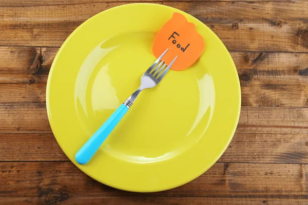 Note paper with message  attached to fork, on plate, on color wooden background — Stock Photo, Image