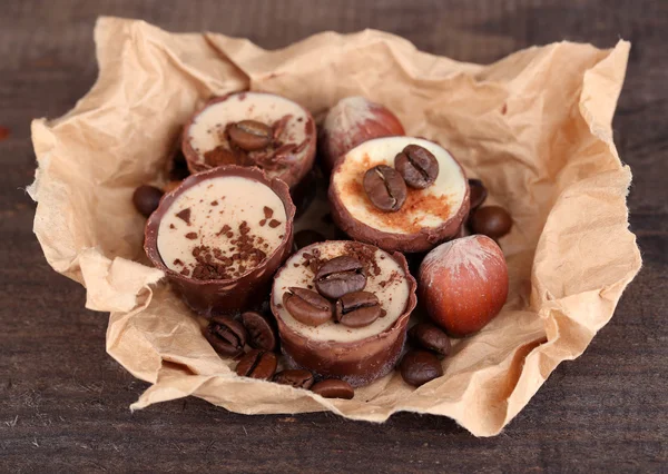 Sabrosos caramelos de chocolate con granos de café y nueces sobre fondo de madera — Foto de Stock