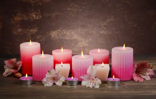Hermosas velas con flores en la mesa sobre fondo marrón —  Fotos de Stock