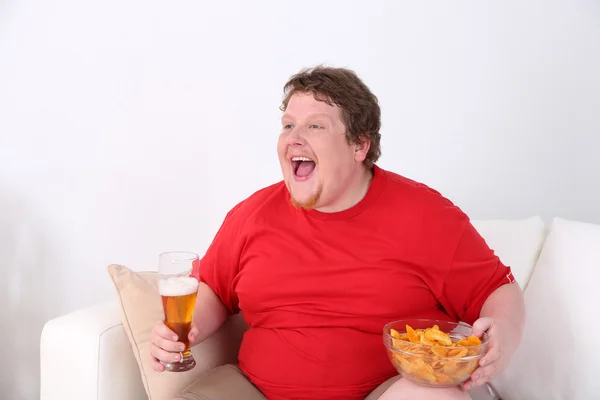 Hombre perezoso con sobrepeso sentado en el sofá y viendo la televisión —  Fotos de Stock