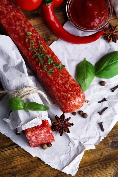 Saporito salame salsiccia e spezie su sfondo di legno — Foto Stock