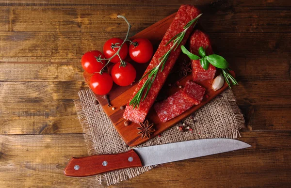 Tasty salami sausage and spices on wooden background — Stock Photo, Image