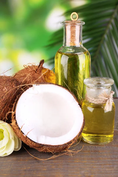 Noci di cocco e olio di cocco sul tavolo di legno, sullo sfondo della natura — Foto Stock