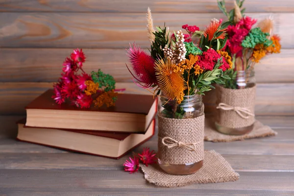 Hermoso ramo de flores brillantes en frascos sobre la mesa sobre fondo gris —  Fotos de Stock