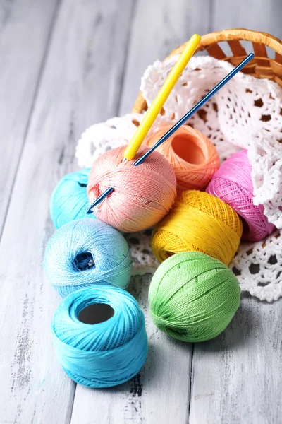 Colorful clews, napkin and crochet hook in wicker basket, on wooden background — Stock Photo, Image