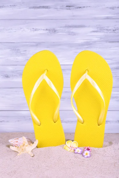 Bright flip-flops on sand, on wooden background — Stock Photo, Image