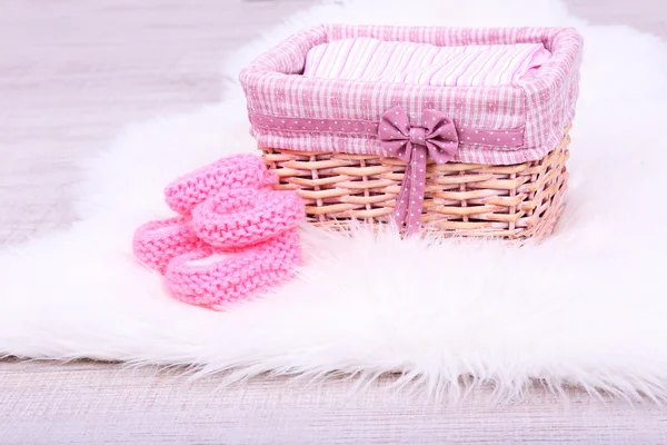 Baby clothes in basket on floor in room — Stock Photo, Image