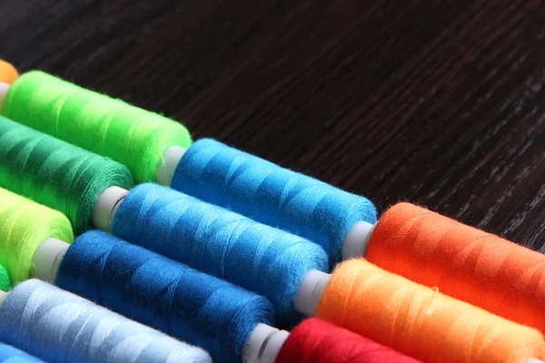 Multicolor sewing threads on wooden background — Stock Photo, Image