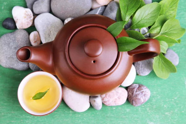 Teapot with dry flowers and herbs ingredients for tea, on stones and color wooden background — Stock Photo, Image