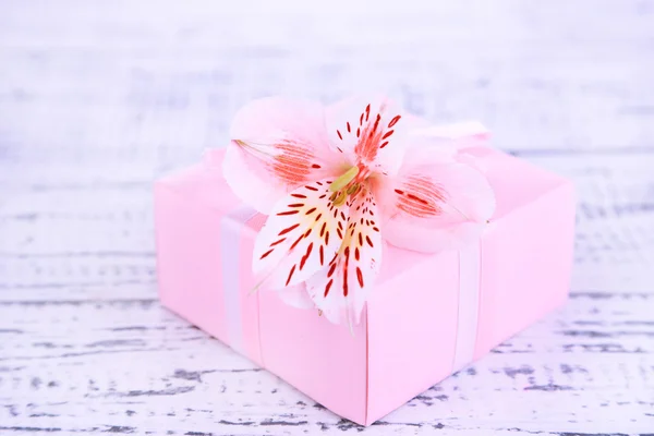 Presente rosa com arco e flor na mesa de madeira close-up — Fotografia de Stock