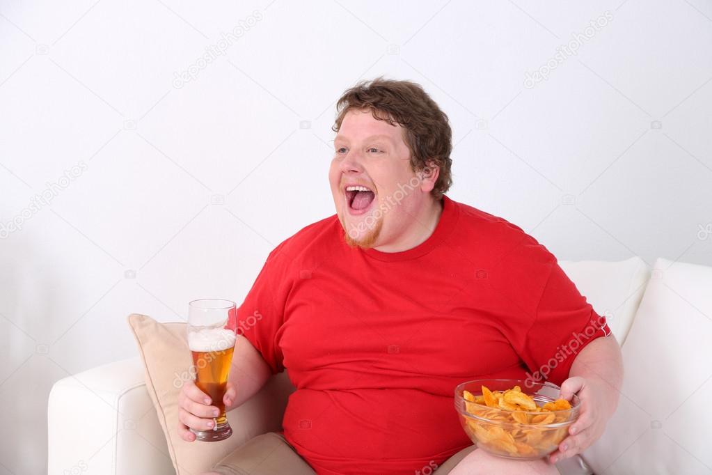 Lazy overweight male sitting on couch and watching television