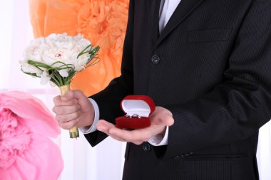 Düğün buketi ve yüzük dekoratif arka planda tutan adam