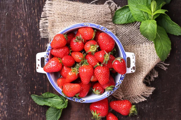 Maturi dolci fragole in pentola su sfondo di legno a colori — Foto Stock