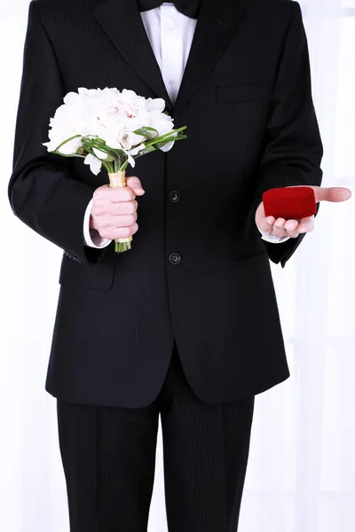 Hombre celebración de ramo de bodas y anillos sobre fondo claro — Foto de Stock