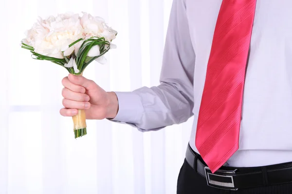 Uomo che tiene bouquet da sposa su sfondo chiaro — Foto Stock