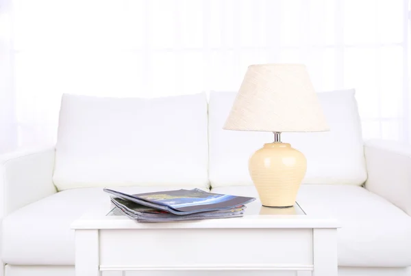 Revistas e lâmpada na mesa de café no quarto — Fotografia de Stock