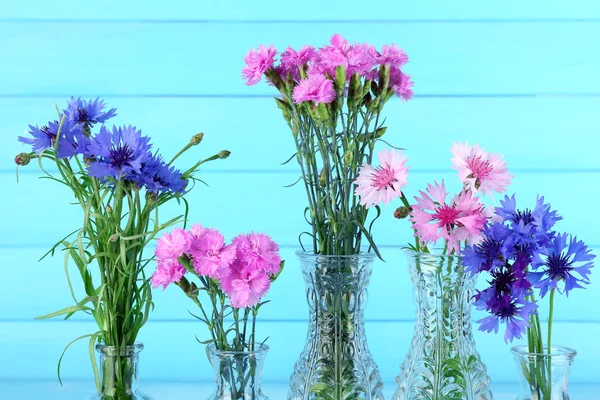 Belles fleurs d'été dans des vases sur fond de bois bleu — Photo