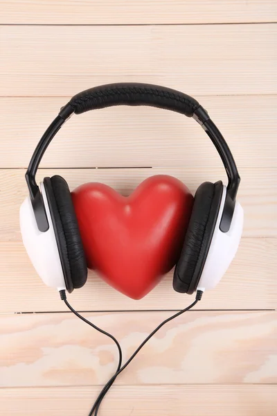 Auriculares y corazón sobre fondo de madera — Foto de Stock