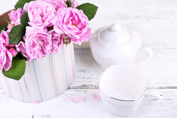 Сніданок чай з чайником свіжих рожевих садових троянд на кольоровому дерев'яному фоні — стокове фото