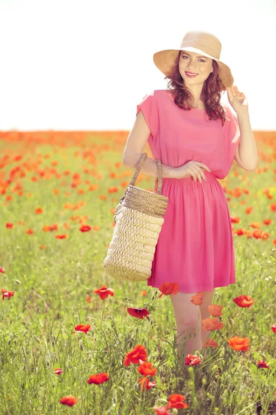 Gyönyörű fiatal nő, fonott szütyőt pipacs mező — Stock Fotó