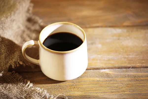 Tazza con caffè caldo e chicchi di caffè torrefatto su sfondo tavolo di legno — Foto Stock