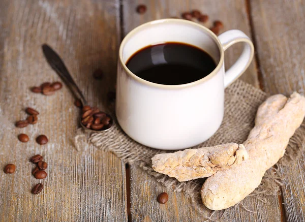Cangkir dengan kopi panas di kain karung serbet, di atas meja kayu latar belakang — Stok Foto