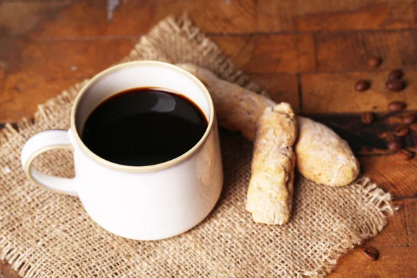 Taza con café caliente en servilleta de saco, sobre fondo de mesa de madera — Foto de Stock