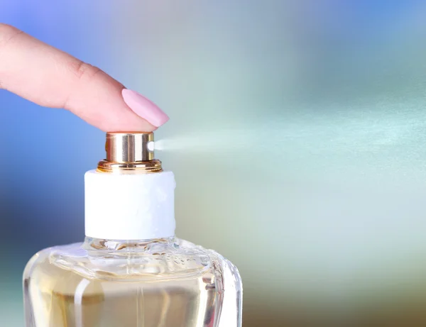 Пляшка парфумів в руці на яскравому фоні — стокове фото