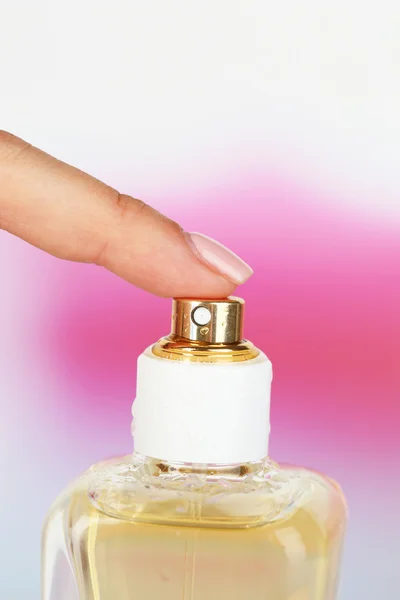 Пляшка парфумів в руці на яскравому фоні — стокове фото