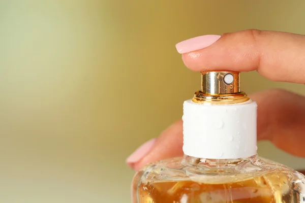 Botella de perfume en mano sobre fondo brillante — Foto de Stock