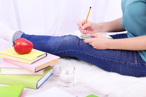 Nahaufnahme einer jungen Studentin, die auf dem Boden sitzt und studiert, auf hellem Hintergrund — Stockfoto