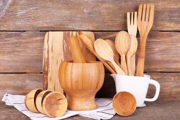 Composition of wooden cutlery, mortar, bowl and cutting board on wooden background — Stock Photo, Image