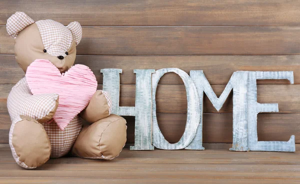 Letras decorativas formando palabra HOME con osito de peluche sobre fondo de madera — Foto de Stock