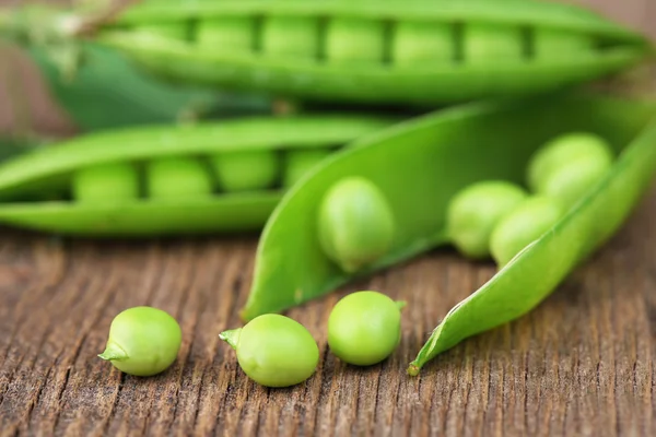 Ervilhas verdes frescas na mesa de madeira — Fotografia de Stock